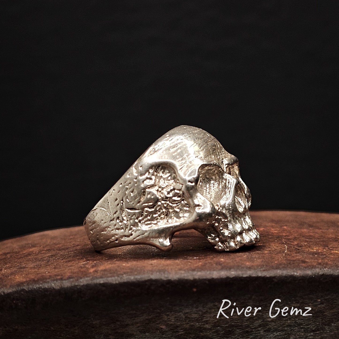 Silver skull ring on a wooden surface with a dark background