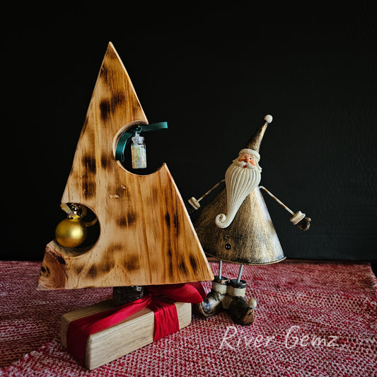 Scorched pine table top Christmas tree with an opal chip ornament and a golden bauble. Photo includes a similarly shaped [triangular] elf.