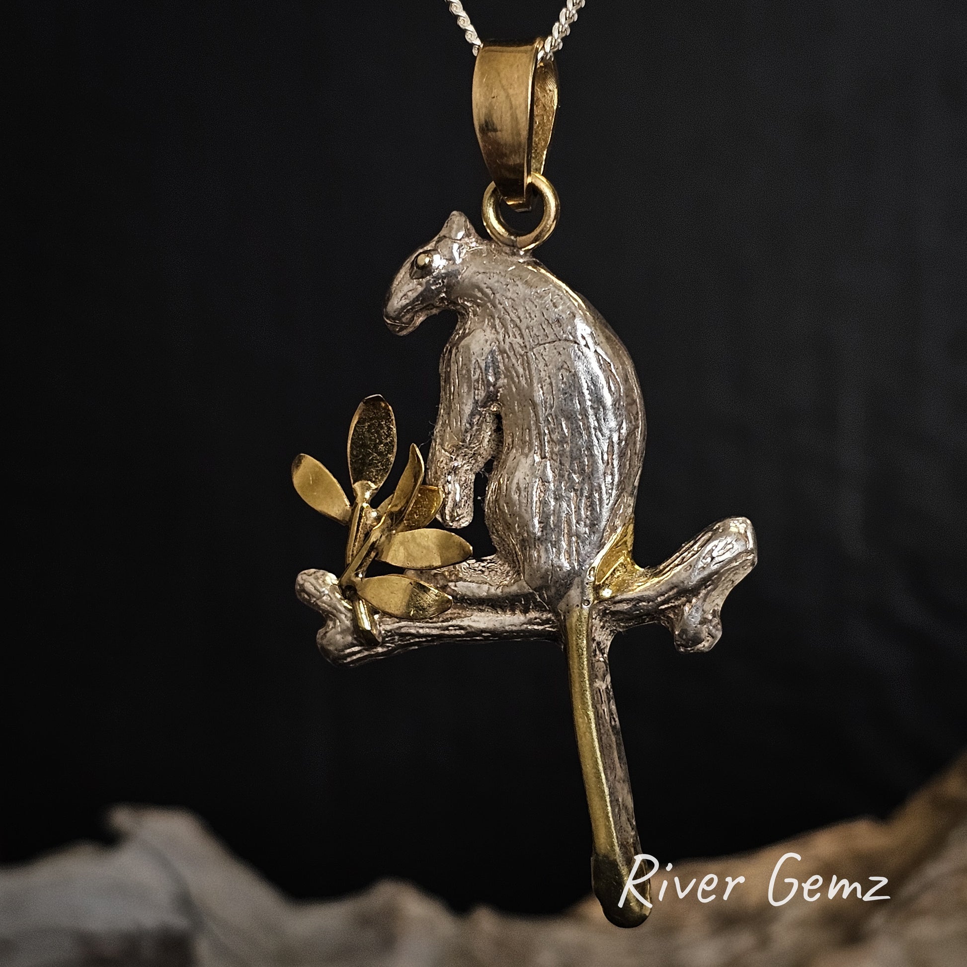 Tree kangaroo pendant with gold and silver finish on a dark background, featuring 'River Gemz' branding.