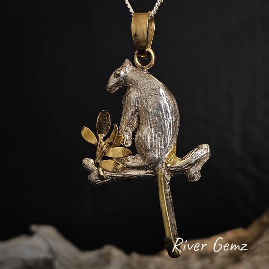 Tree kangaroo pendant with gold and silver finish on a dark background, featuring 'River Gemz' branding.