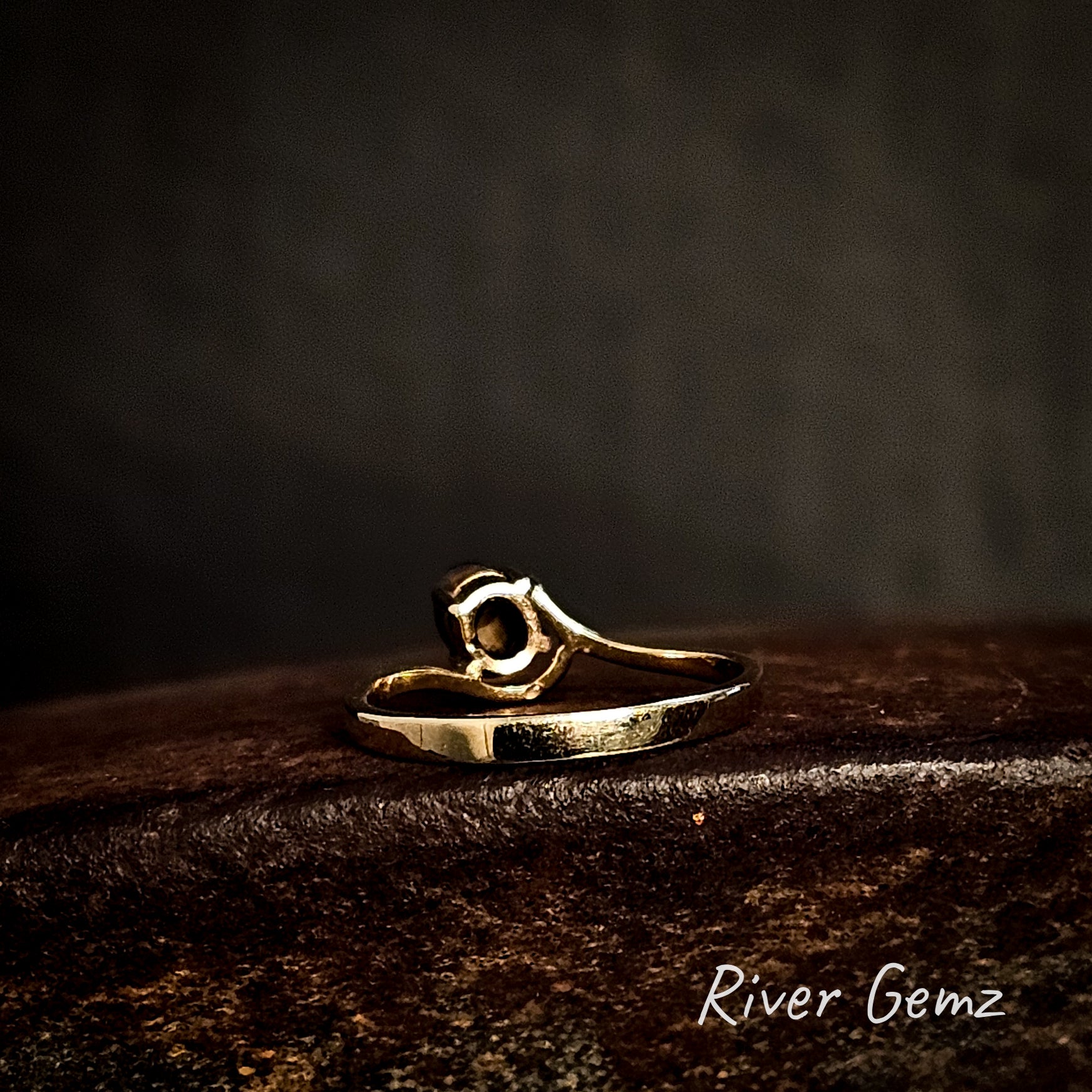Back of gold ring showing the ironstone matrix of the boulder opal on a dark surface with 'River Gemz' branding.