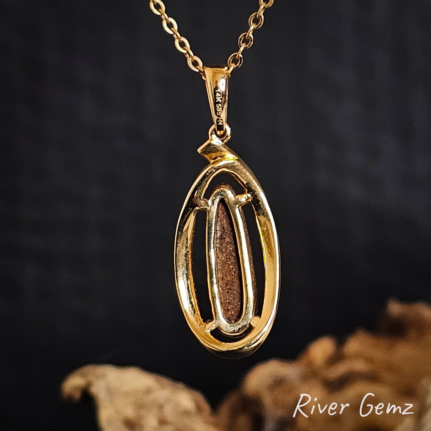 Rear of gold pendant shows the ironstone matrix of the inserted boulder opal on a dark background, featuring 'River Gemz' branding.
