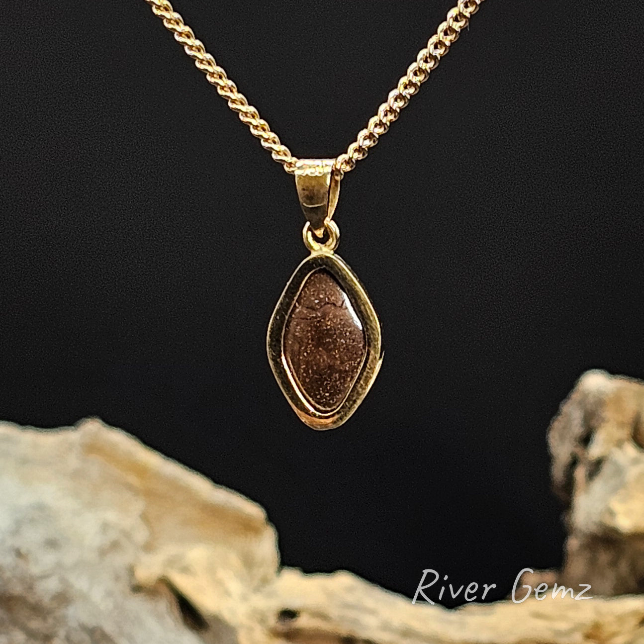 Rear view of gold necklace shows the ironstone matrix of the boulder opal on a black background
