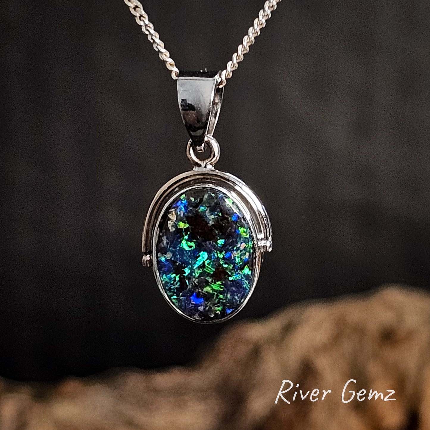 Necklace with a pendant featuring a blue and green black boulder opal on a dark background, branded 'River Gemz'.