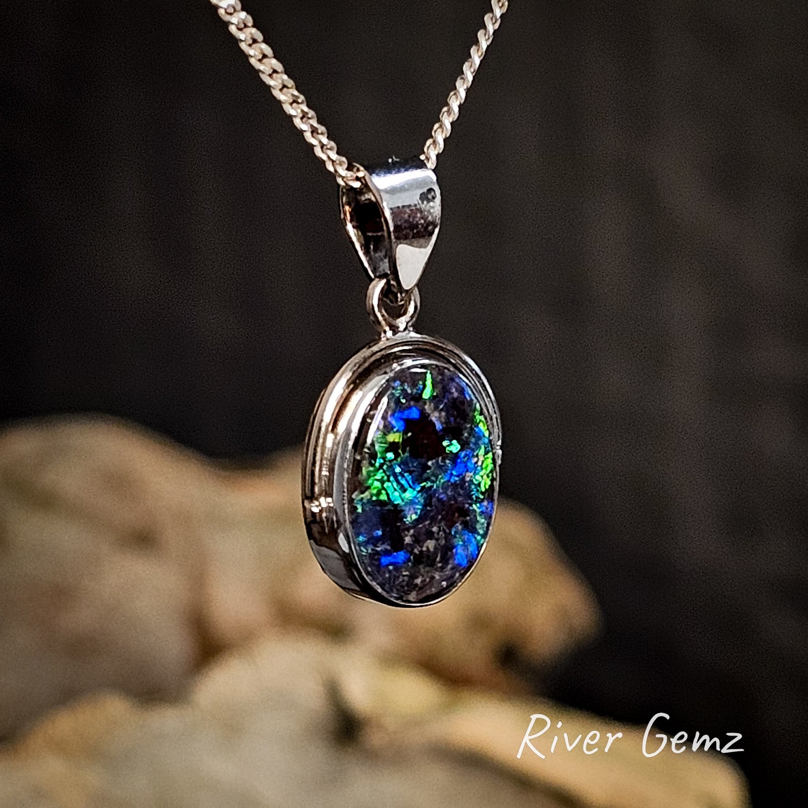 Opal pendant necklace on a chain with a blurred natural background.