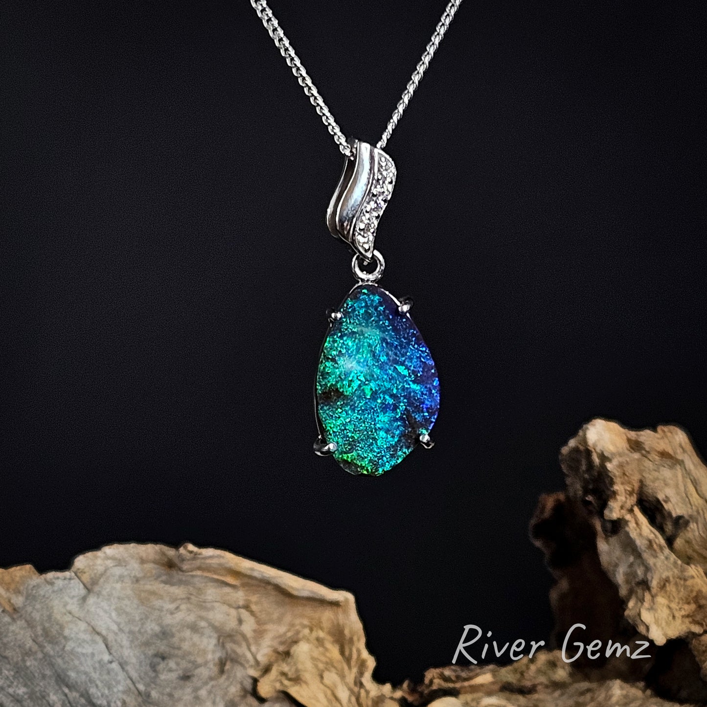 Blue and green boulder opal claw set in white gold pendant on a dark background with 'River Gemz' branding.