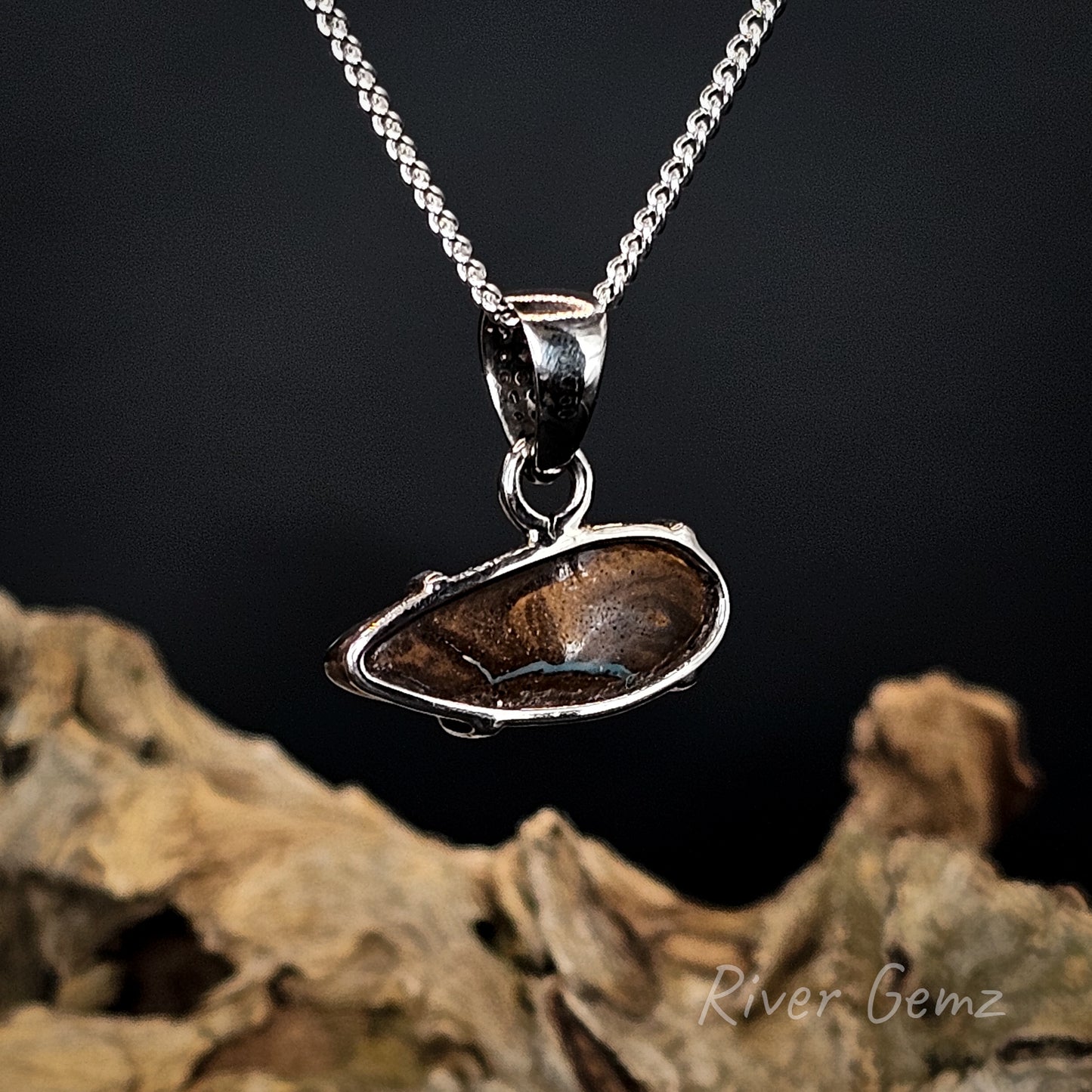 Rear view of the white gold pendant showing the ironstone matrix of the boulder opal set within it.