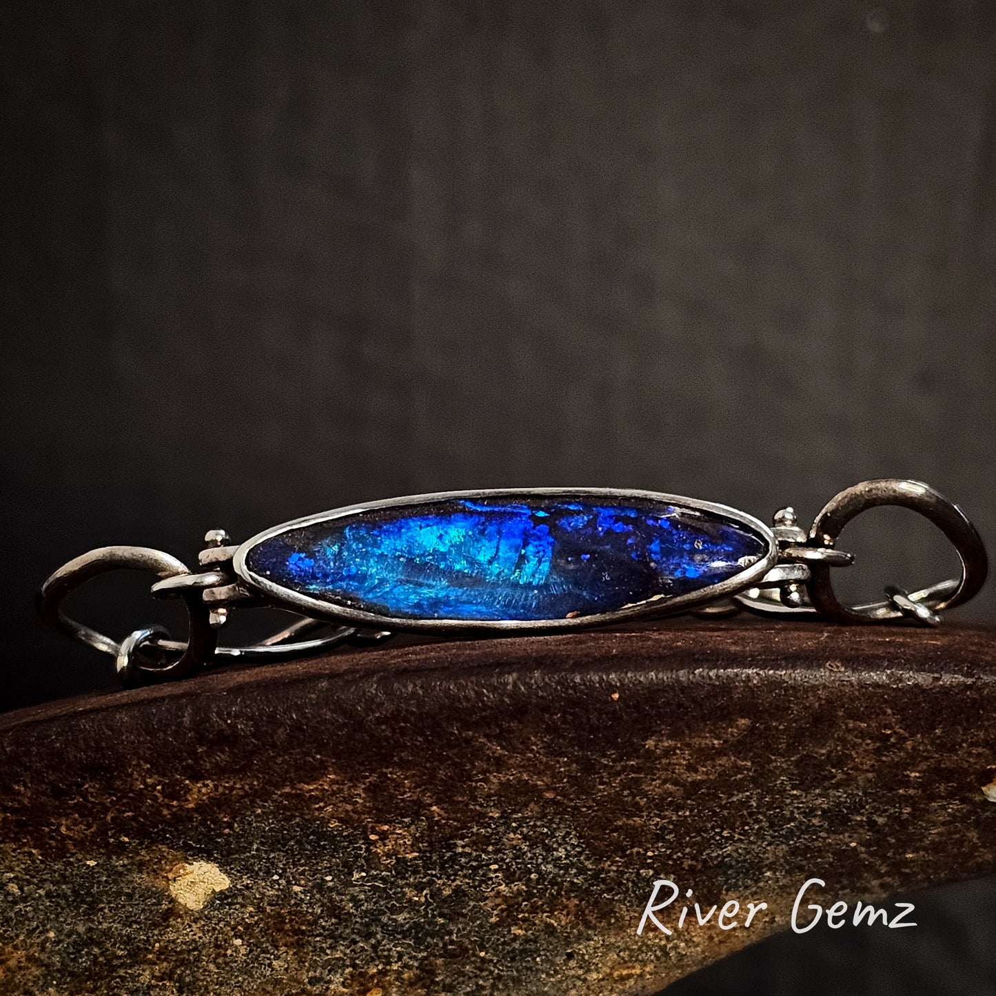 Bracelet with blue opal and silver frame on a dark background, featuring 'River Gemz' branding.