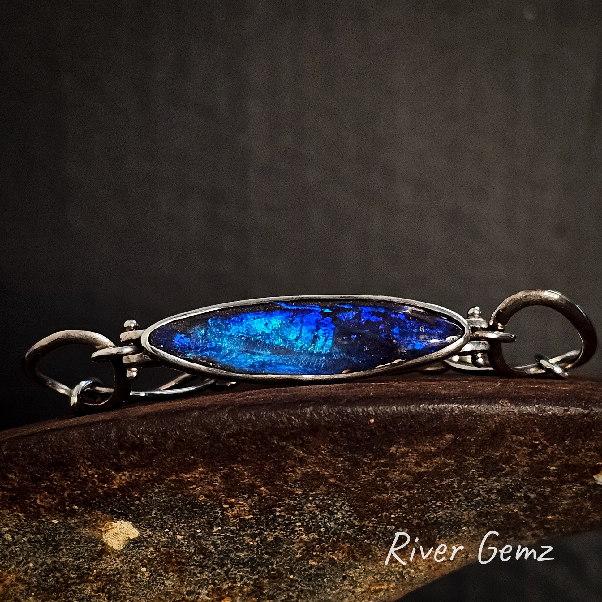 Bracelet with blue opal and silver frame on a dark background, featuring 'River Gemz' branding.
