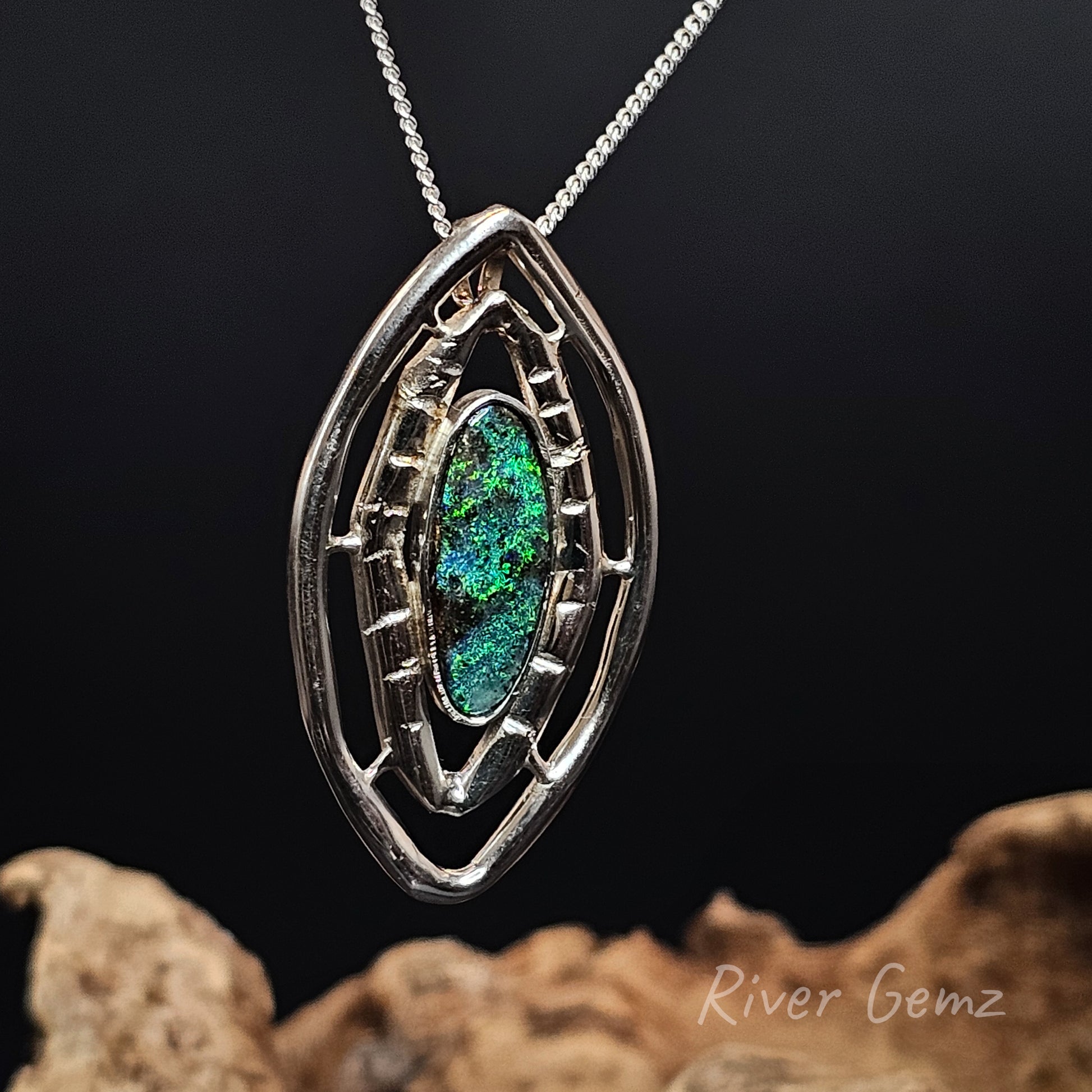Dark green opal besel set in a leaf shaped silver necklace on a dark background