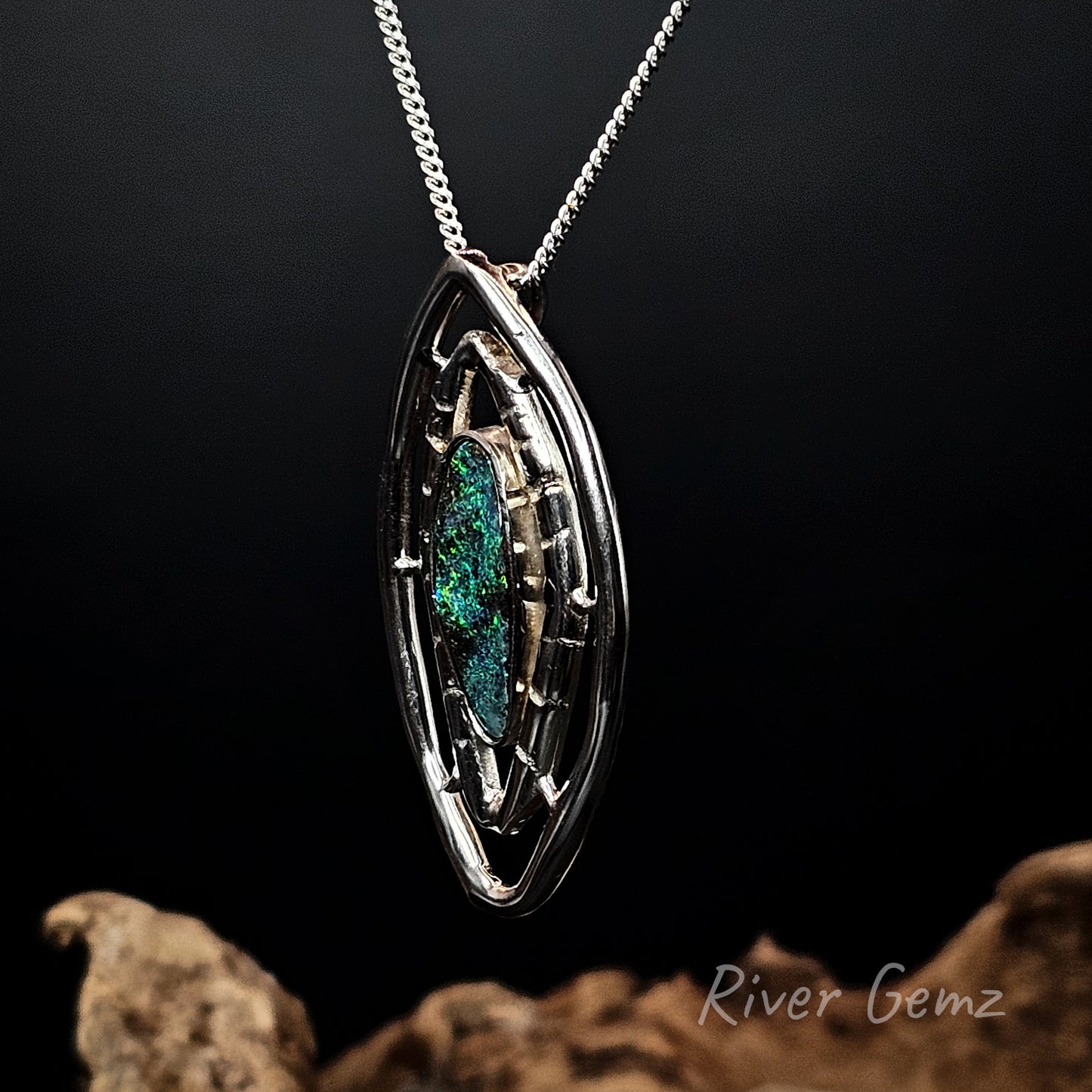 Silver pendant with green gemstone on a dark background