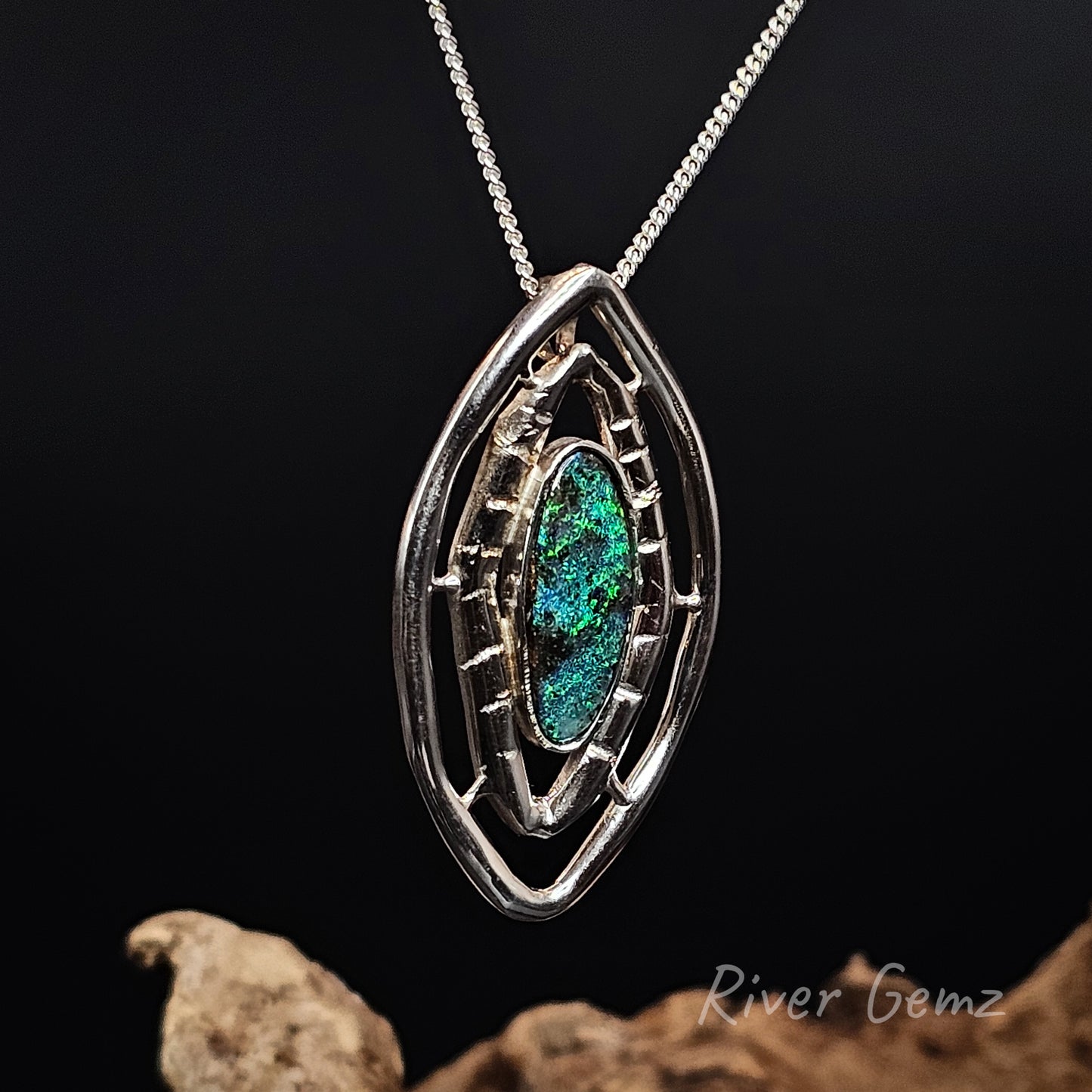 Silver pendant with a green gemstone on a dark background