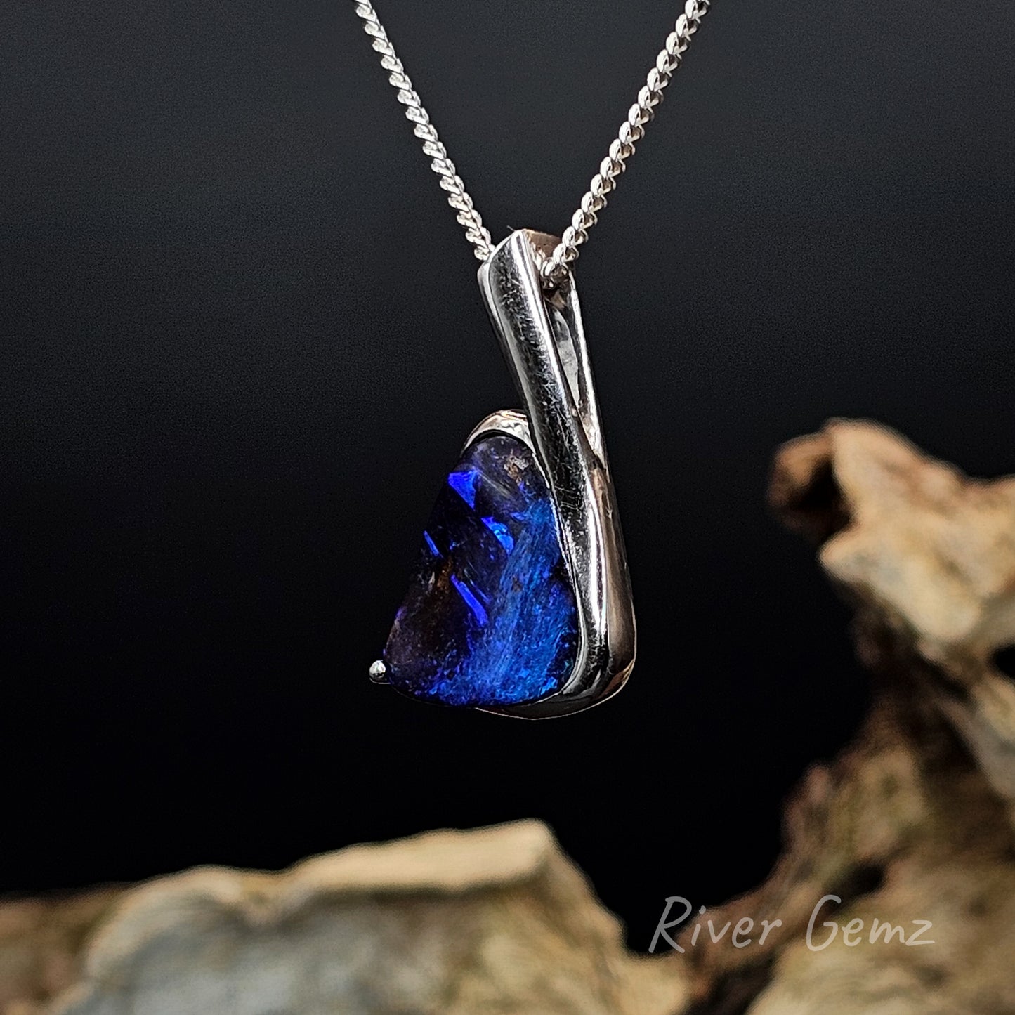 Blue opal set in sterling silver pendant  on a dark background with 'River Gemz' branding.