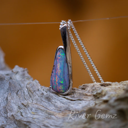 Tear-drop shaped opal with lots of colour showing. The bail is cleverly integrated with the j-shaped setting.