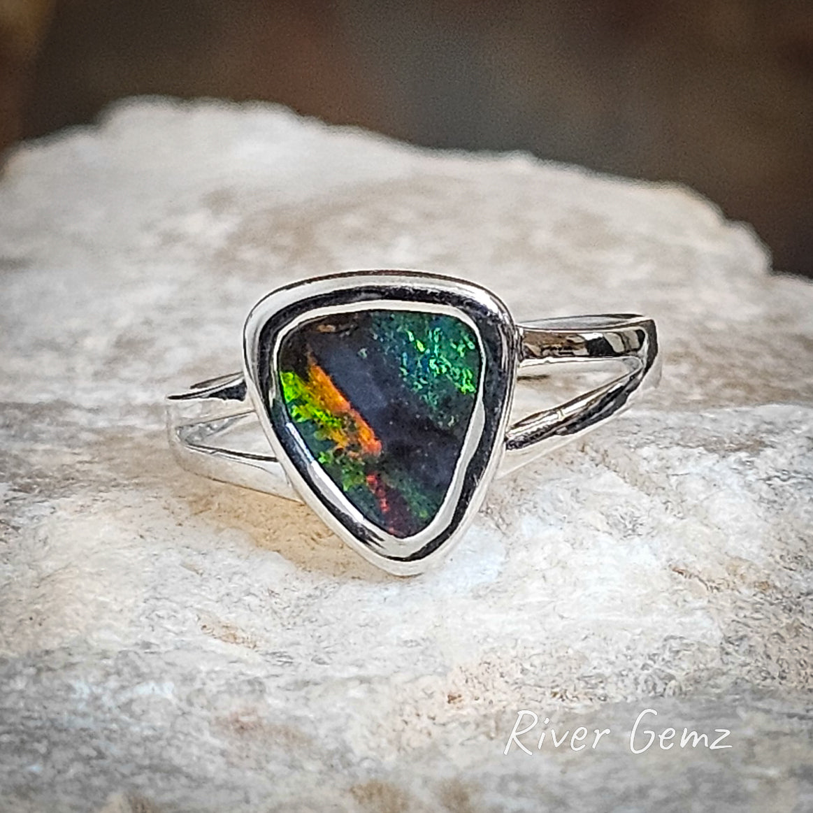 Triangular shaped green and blue boulder opal with fire orange splash set in silver ring.