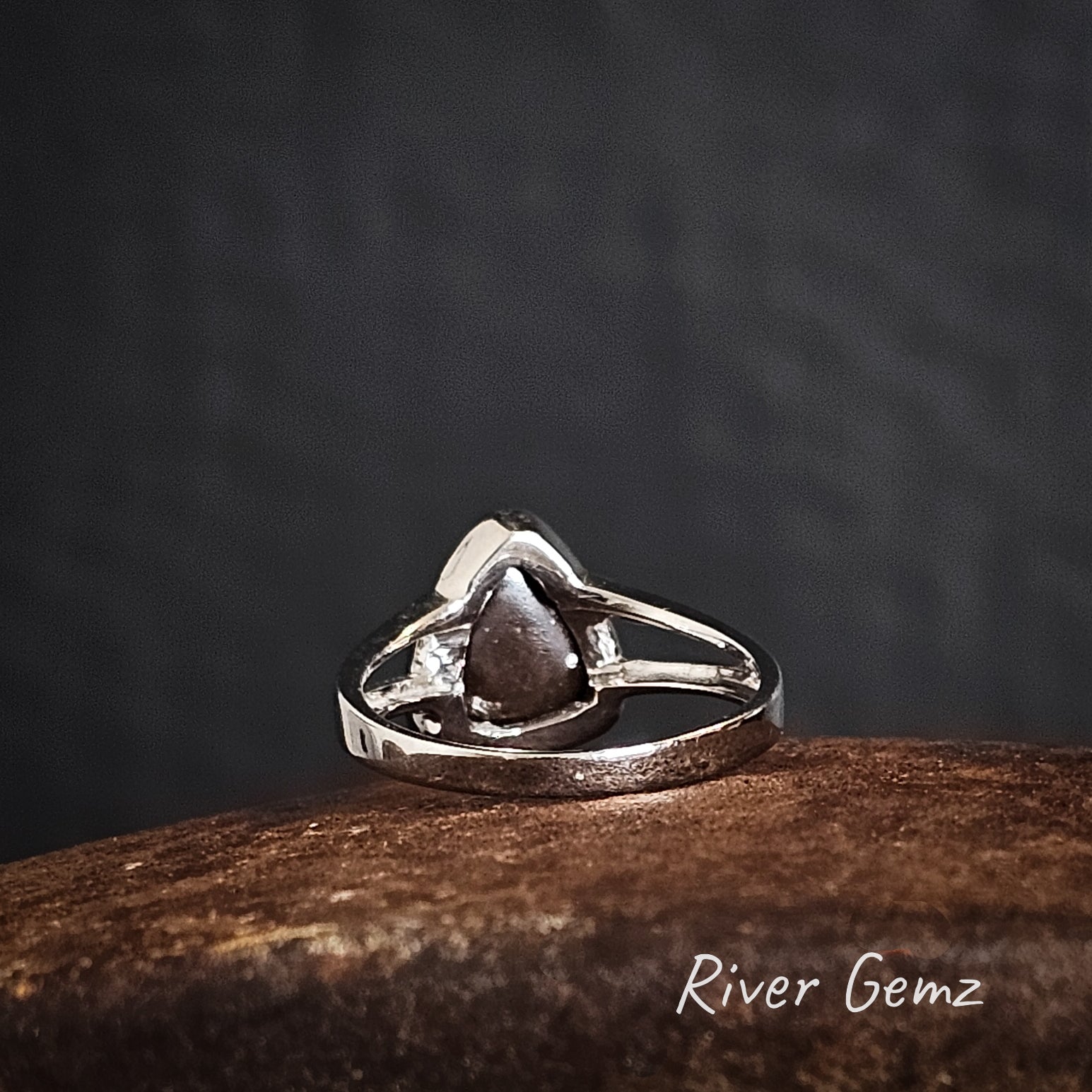 Back view of silver ring showing the ironstone matrix of the inserted boulder opal on a dark background, branded 'River Gemz'.
