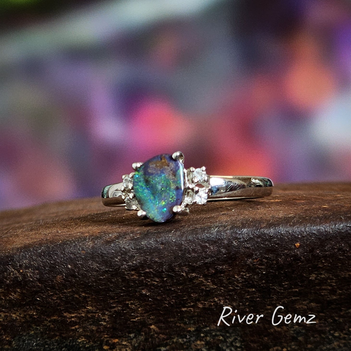 Triangular shaped boulder opal with 4 white topaz claw set in silver ring.