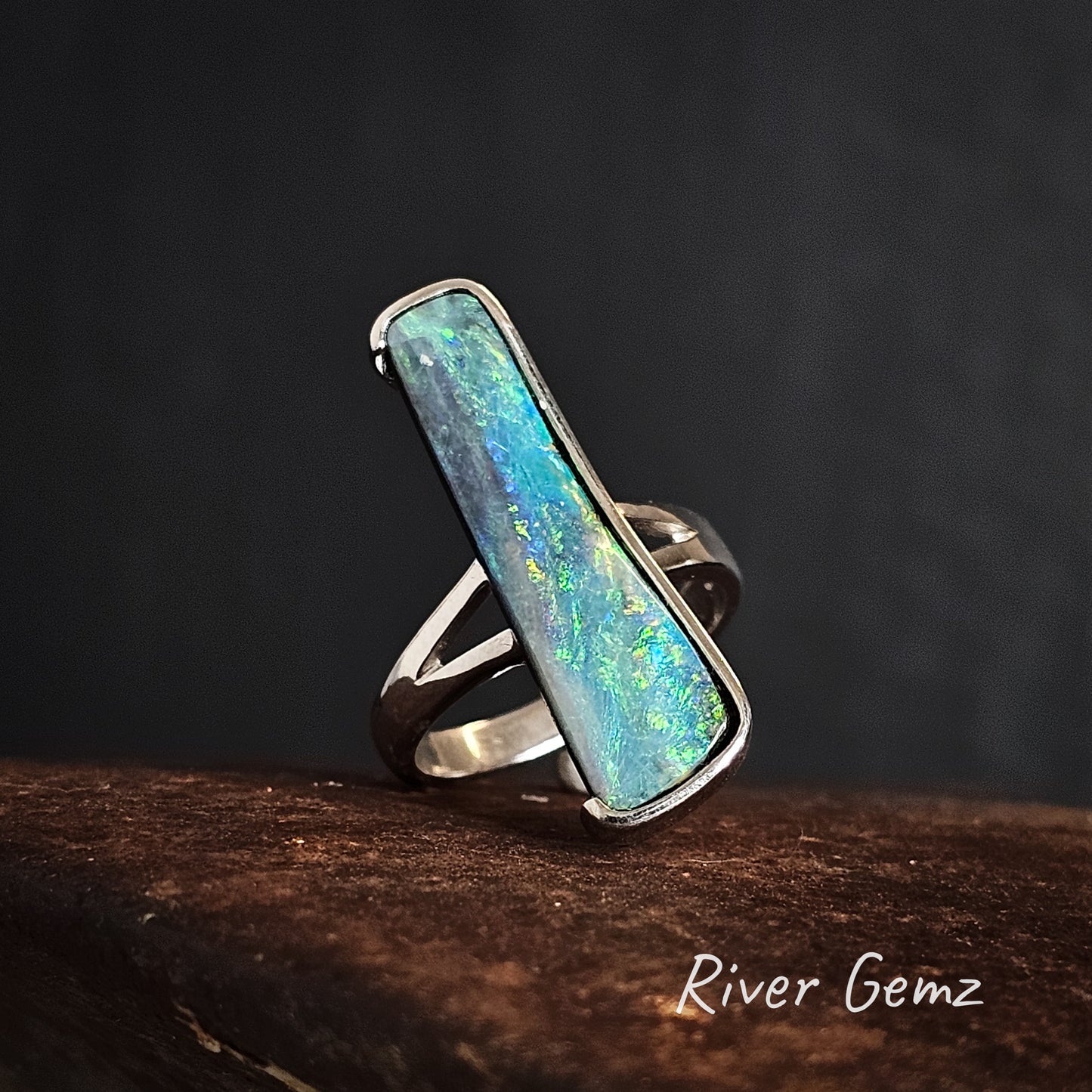 Opal ring with silver setting on a dark background, branded 'River Gemz'.
