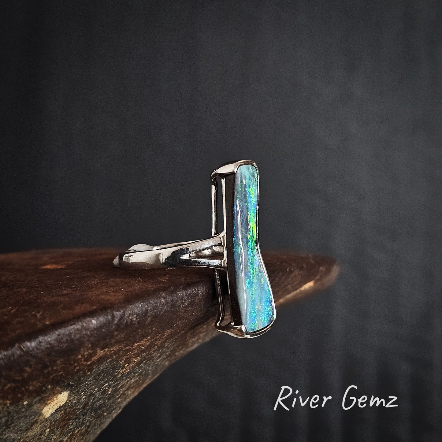 Side view of the sterling silver ring with a blue and green opal stone on a dark background, branded 'River Gemz'.