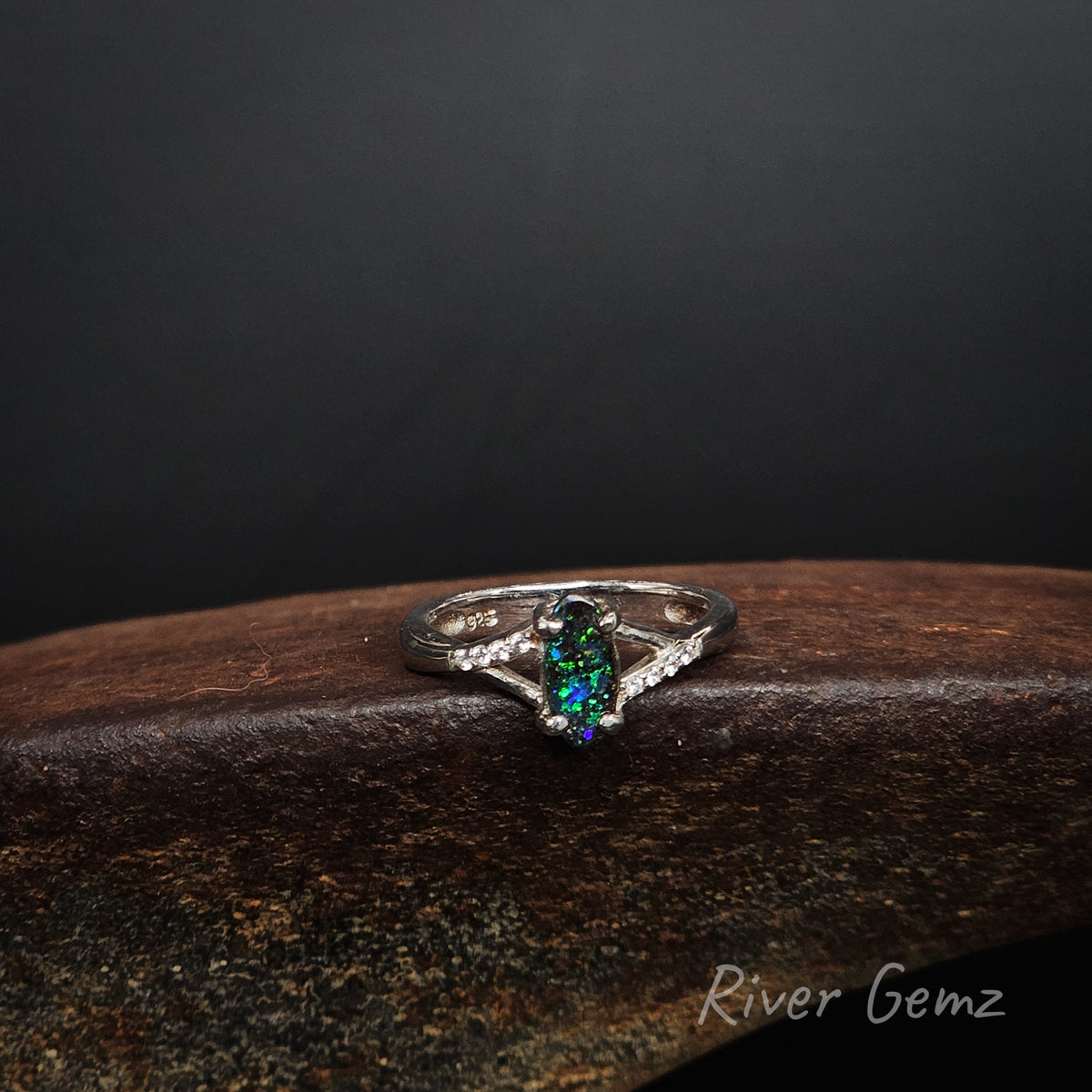 Predominantly green coloured boulder opal and white topaz stones claw set in a sterling silver ring with uniform width for the ring's band.
