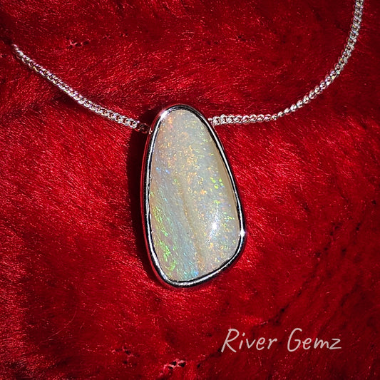 Multicoloured pipe opal set in sterling silver necklace photographed on a red Christmas hat.