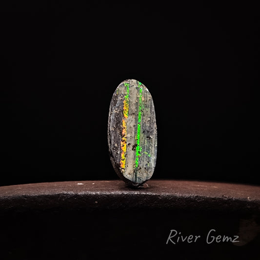 Unset boulder opal with two colorful veins on a dark background, labeled 'River Gemz'.