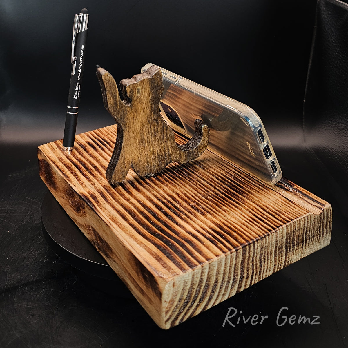 Phone resting against a cat on a torched wooden base which includes a black stylus.