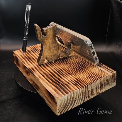 Phone resting against a cat on a torched wooden base which includes a black stylus.