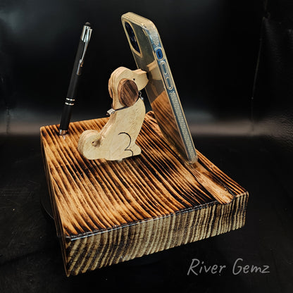 Wooden dog phone/tablet stand. Dog is in sit position with a mobile phone leaning against it's nose.