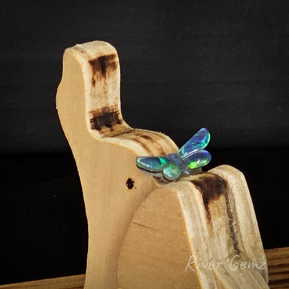 Wooden holder with a butterfly-shaped opal stone on a dark background