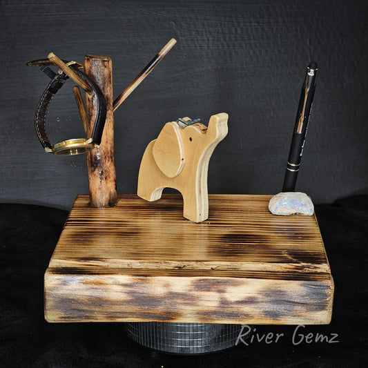 Wooden elephant stand with a pen and other items on a dark background, branded 'River Gemz'.