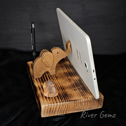Wooden elephant stand holding a tablet and pen on a black background with 'River Gemz' branding.