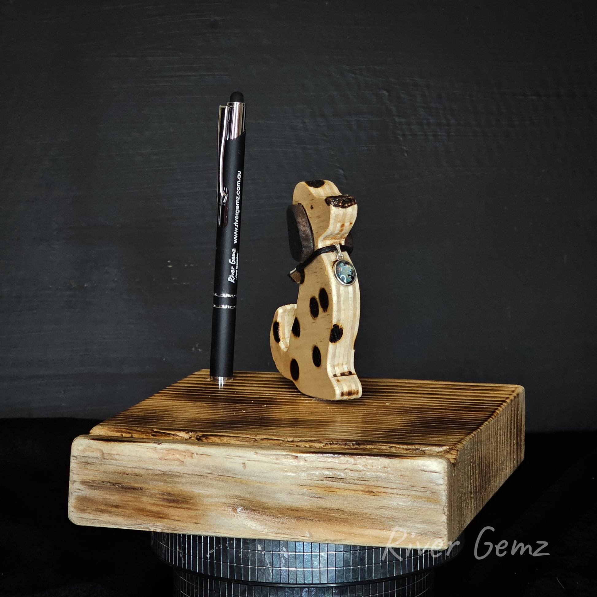 Wooden phone and tablet stand with a pen and dog with opal dog tag on a dark background