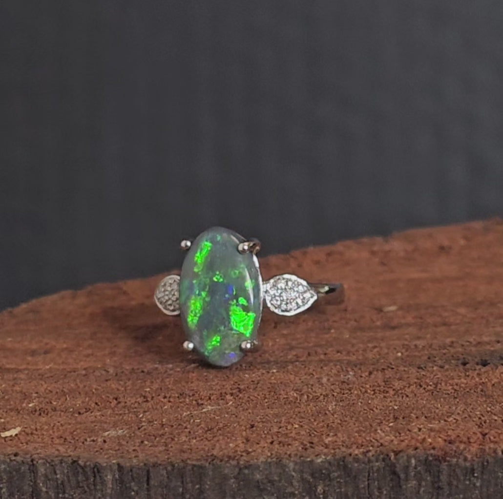 Video showing white gold ring with black opal and diamonds rotate 180 degrees.