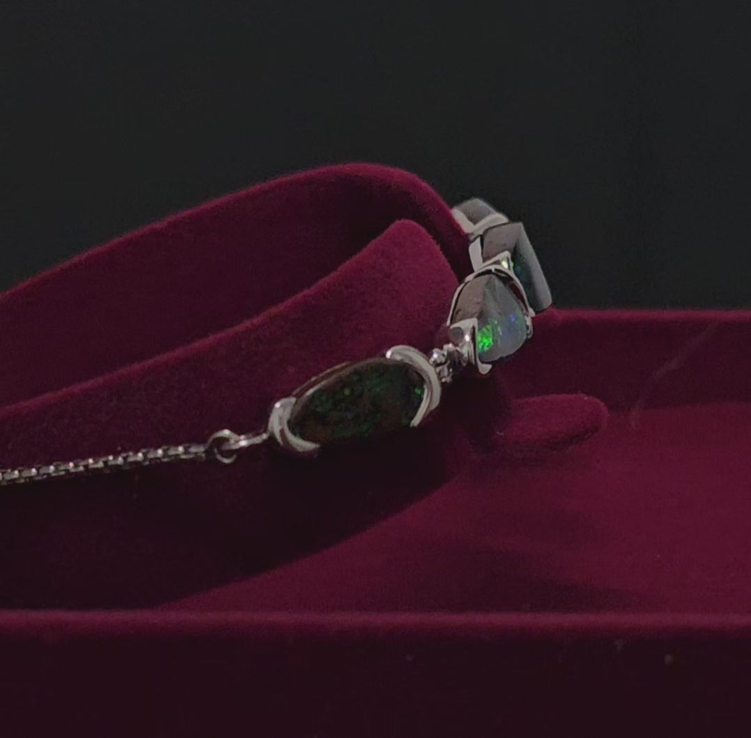 Silver bracelet with 5 dark opals in a moroon velvet box rotating 180 degrees in this video.