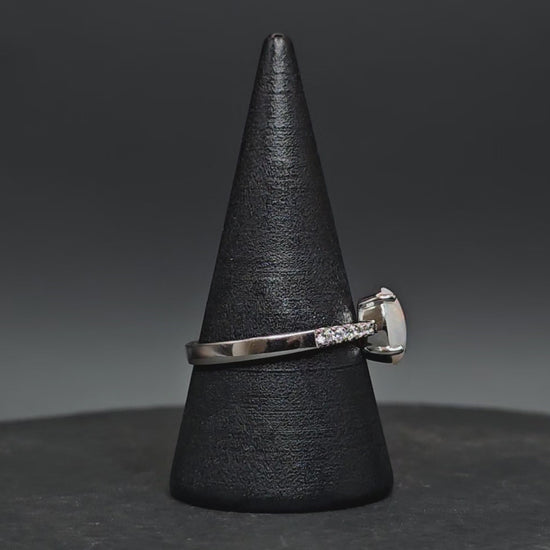 Video showing the white opal sterling silver ring rotate on a cone shaped ring display.