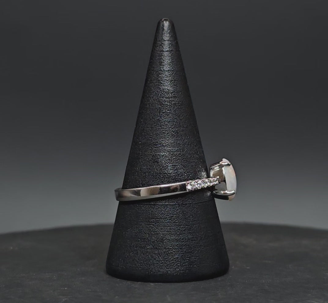 Video showing the white opal sterling silver ring rotate on a cone shaped ring display.