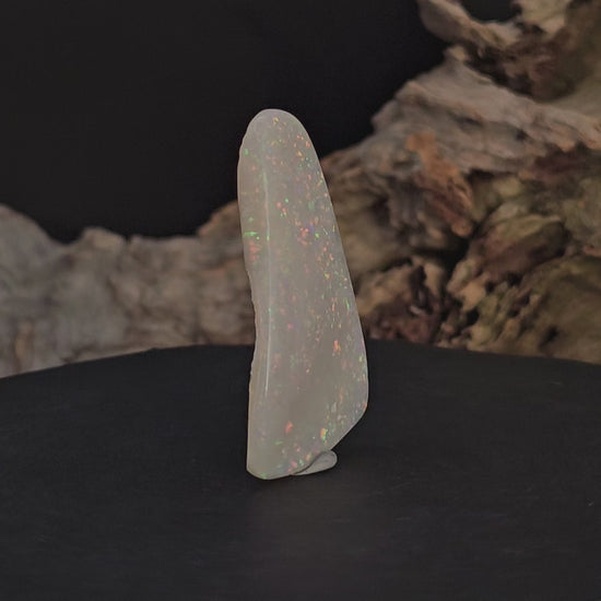 Video showing large opal standing upright rotate to show all faces/sides of the white opal.