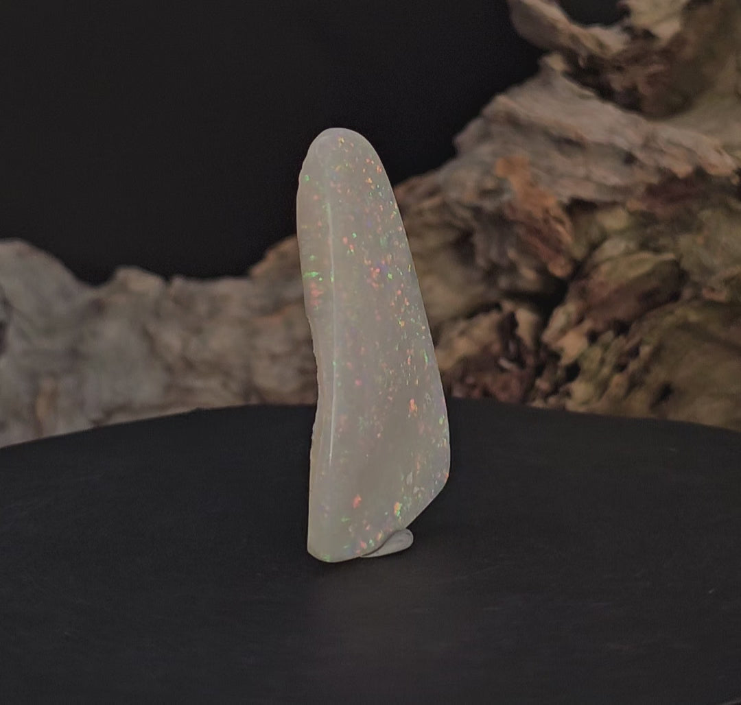 Video showing large opal standing upright rotate to show all faces/sides of the white opal.