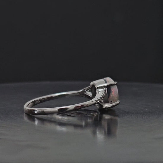 Video showing silver ring laying on a black surface rotating 360 degrees.