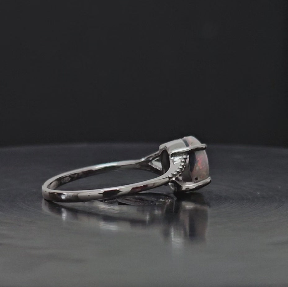 Video showing silver ring laying on a black surface rotating 360 degrees.