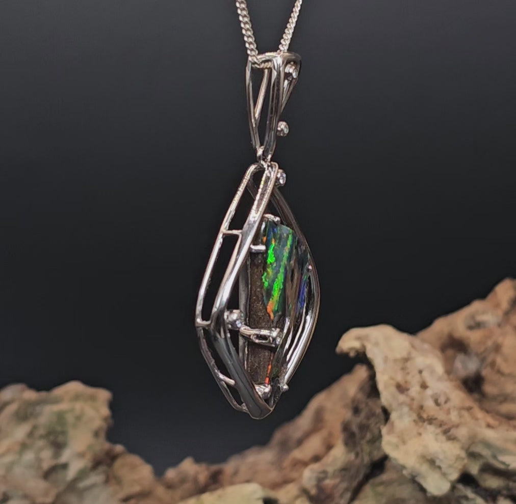 Video showing large multi-coloured dark opal rotate 200 degrees showing all faces of the opal.