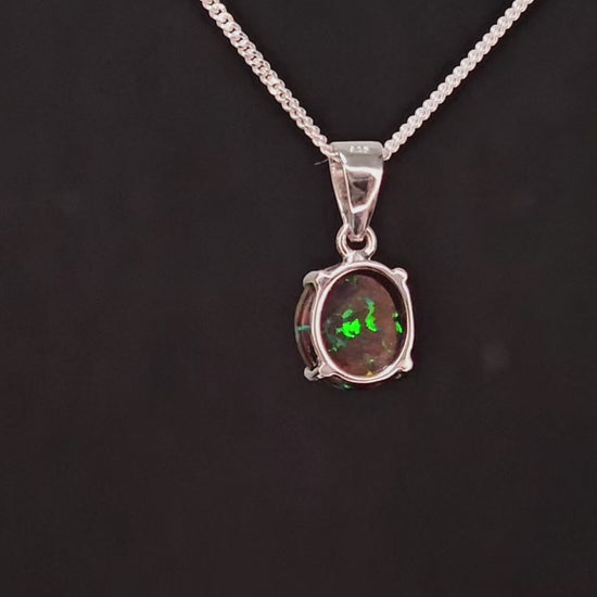 Small round earthy opal with veins of colour embedded set in a silver necklace.