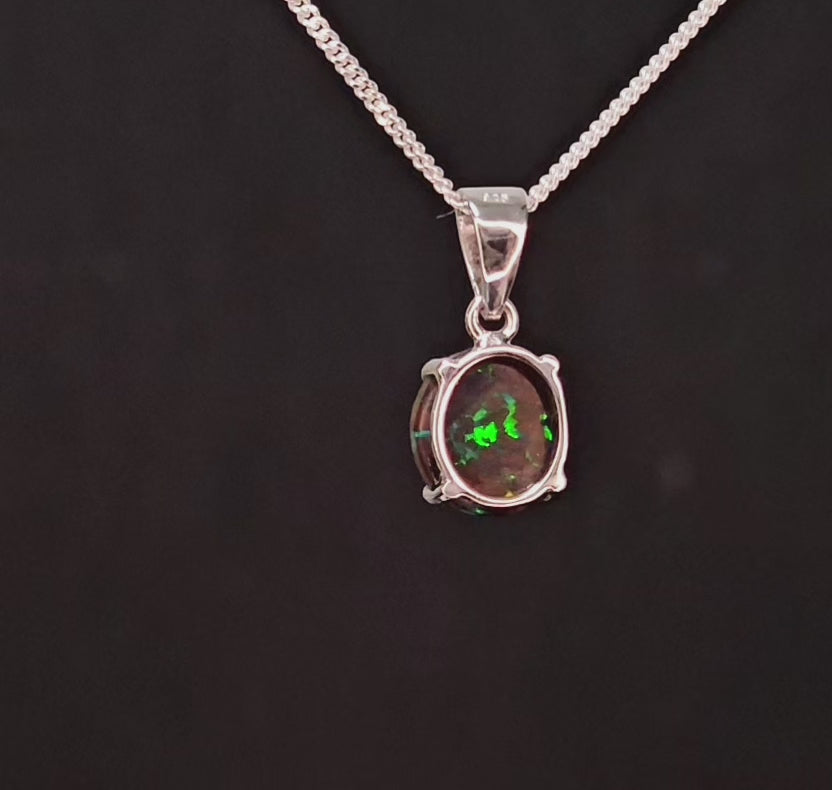 Small round earthy opal with veins of colour embedded set in a silver necklace.