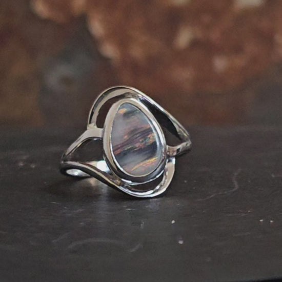 Video showing dark opal with sky pink  and grey colours like a sunset in a silver ring rotating 180 degrees.