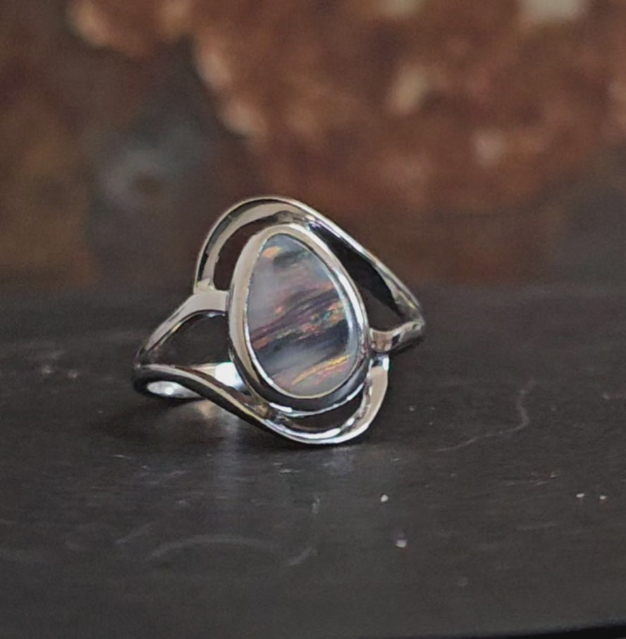 Video showing dark opal with sky pink  and grey colours like a sunset in a silver ring rotating 180 degrees.