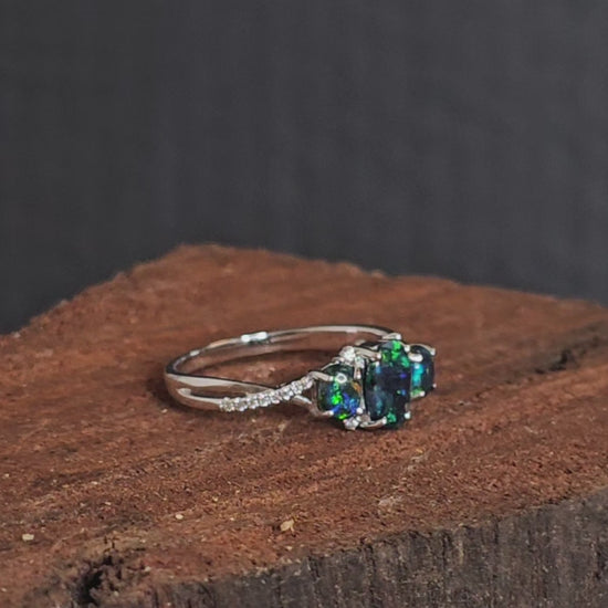 Video showing the tri-black opal and diamond white gold ring rotate 180 degrees.