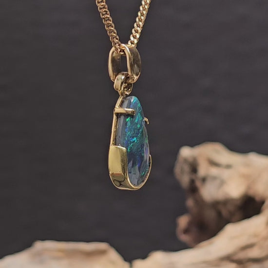Video showing the yellow gold necklace with a tear-drop shaped dark opal rotate 180 degrees.