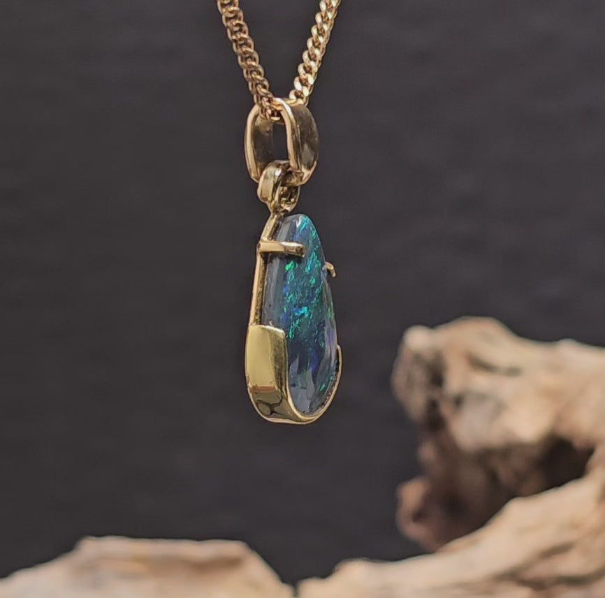 Video showing the yellow gold necklace with a tear-drop shaped dark opal rotate 180 degrees.