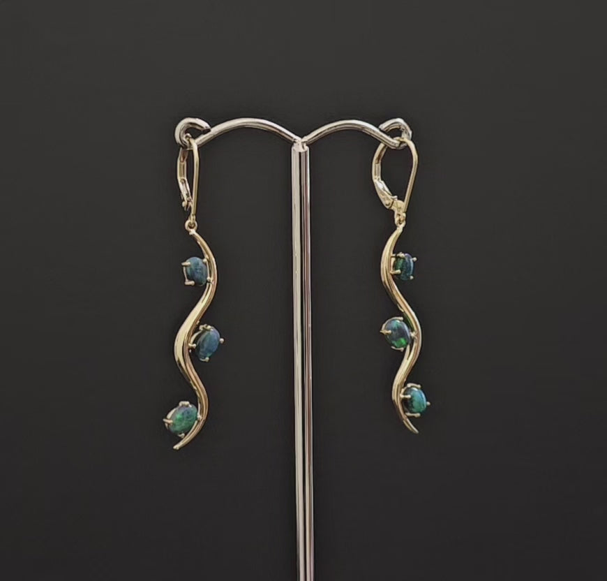 3 dark opals claw set in long dangly gold earrings. Snake like track design with the 3 opals alternating sides of the track.